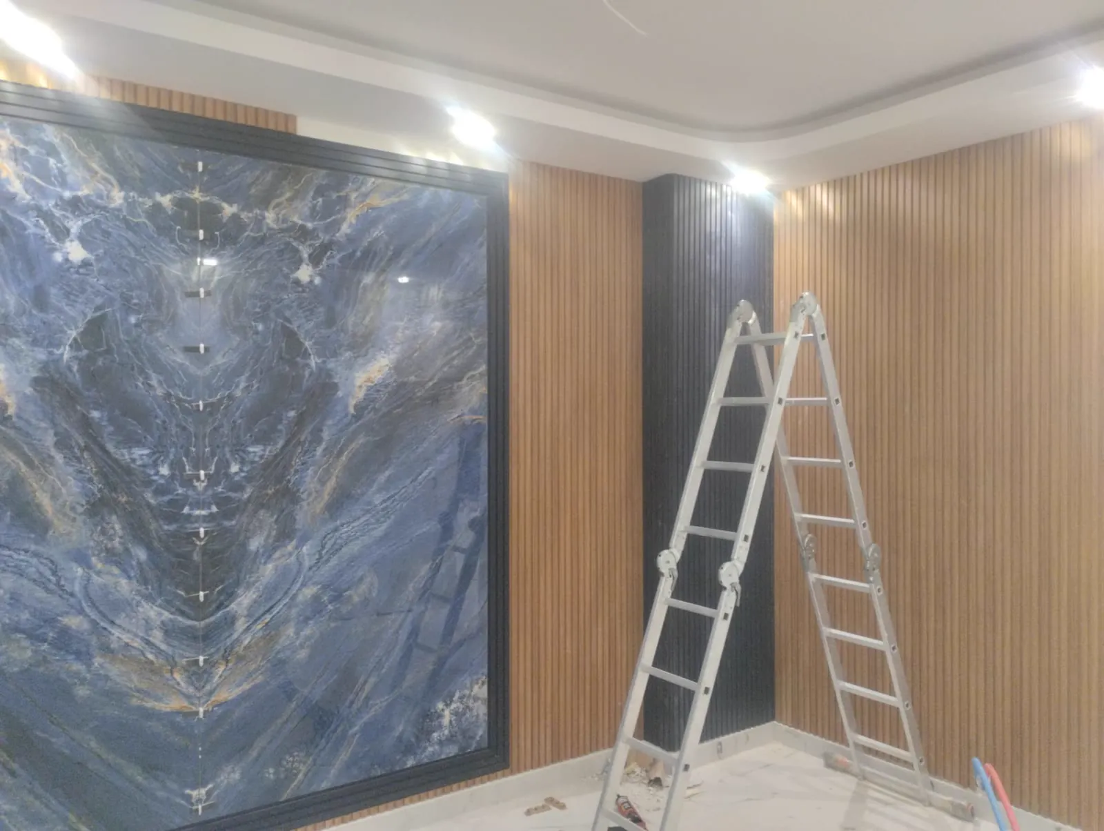 Arkadan aydınlatmalı mavi mermer duvar ve çıtalı ahşap paneller